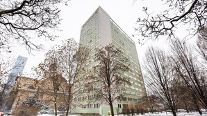 Un edificio alto con varios pisos, rodeado de árboles sin hojas y un suelo cubierto de nieve.