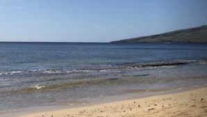 A beach with clear blue water and a sandy shore.