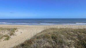 Una spiaggia con cielo sereno, dune sabbiose e l'oceano.