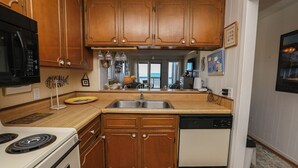 Cucina con pensili e basi in legno, forno a microonde, piano cottura e lavastoviglie.