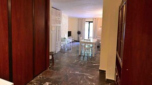 Un pasillo con suelo de mármol que conduce a un comedor con mesa y sillas.