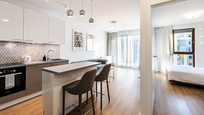 A modern kitchen with white cabinets, a hexagonal backsplash, and a central island with bar stools. - Wola Bloom Apartment (Warszawa)
