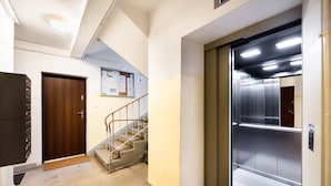 An interior hallway with a wooden door, a staircase, and an elevator. - Żoliborz Elite Apartment (Warszawa)