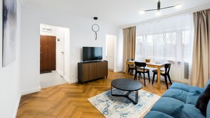 A modern living room with a TV, sofa, dining table, and chairs.