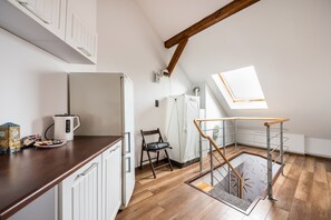 Kitchen area with a refrigerator, wooden floor, and skylight above the window.