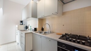 Een moderne keuken met witte kasten, een roestvrijstalen spoelbak en een gasfornuis.