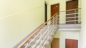 Een trap met een houten leuning en metalen spijbels, die uitkomt op een plateau met twee houten deuren.