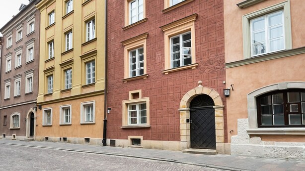 A row of multi-story buildings with uniform window designs and a cobblestone street. - Old Town Basilisk Apartment (Warszawa)