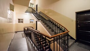 A staircase with a wooden handrail and black metal balusters, leading to an upper floor. - Old Town Basilisk Apartment (Warszawa)