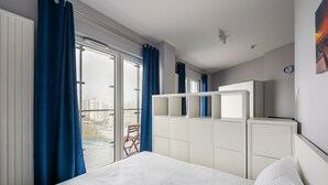 Een hotelkamer met een bed, een kledingkast, een raam met gordijnen en uitzicht op de stad.