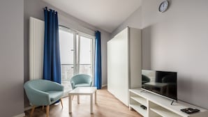 Een moderne woonkamer met een televisie, een bank, een salontafel en een raam met gordijnen.