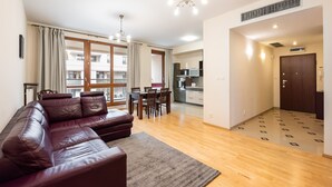 Eine moderne Wohnung mit Ledersofa, Essbereich, Küche und einem Balkon mit Aussicht.