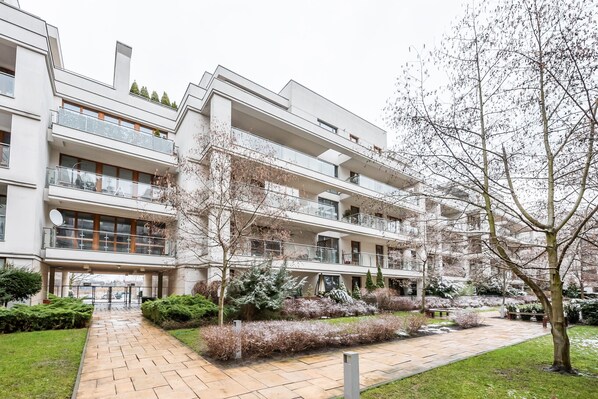 Un edificio residencial de varios pisos con balcones, un patio central y abundante vegetación circundante.