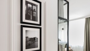 A modern living room with a wooden floor, a white wall with two framed black-and-white photographs, and a glass door leading to another room. - Plac Politechniki Pistachio Apartment (Warszawa)