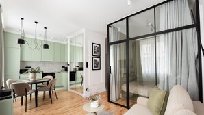 A modern living room with a sofa, a dining table with chairs, and a kitchen in the background. - Plac Politechniki Pistachio Apartment (Warszawa)