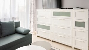 A modern living room with a grey sofa, a white coffee table, and a white cabinet with drawers. A flat-screen TV is mounted on the wall above the cabinet. - Praga-Południe Czechowicka Apartment (Warszawa)