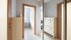 A hallway with a wooden door, a white dresser, and a small desk with a chair. - Praga-Południe Czechowicka Apartment (Warszawa)