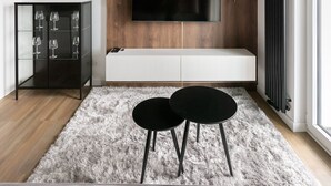 Un salon moderne avec un mur d’accent en bois, un téléviseur fixé au mur, une vitrine contenant des verres à vin et un tapis moelleux.