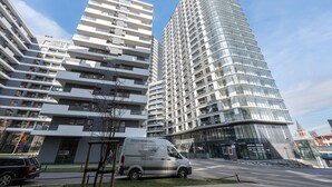 Un bâtiment moderne à plusieurs étages, un fourgon devant, et un ciel dégagé.