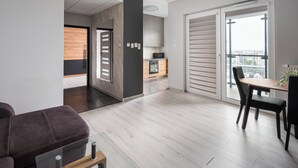 A modern apartment with a dining area, a kitchen, and a balcony with a city view. - New Varsovia Comfort 1604 (Warszawa)