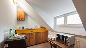 Une cuisine de taille réduite, équipée d’un four à micro-ondes, de meubles en bois, d’un évier et d’une fenêtre.