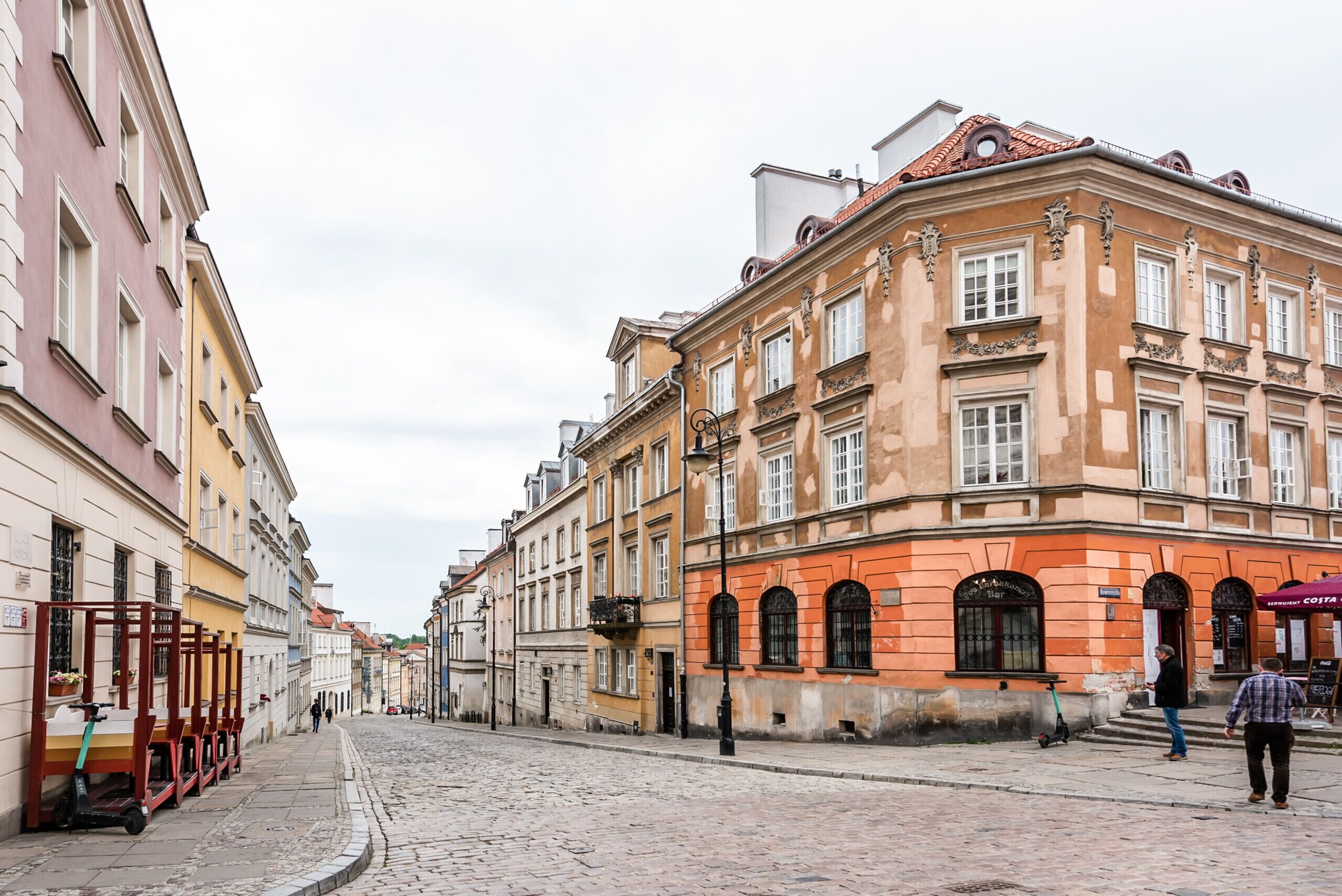 Une rue pavée bordée de bâtiments historiques à l’architecture classique, sous un ciel dégagé.