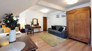Un salon avec une table à manger en bois, un canapé bleu, une armoire en bois et un tapis vert.
