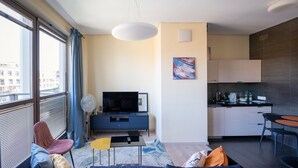 Een modern appartement met een woongedeelte, kitchenette en grote ramen.