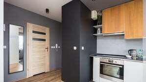 A modern kitchen with a built-in oven, wooden cabinets, and a grey backsplash. - Arte Praga Koneser Apartment (Warszawa)