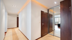 Un couloir doté d’un plancher en bois, de murs blancs et d’une porte coulissante en verre donnant sur une pièce.