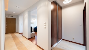 Un couloir moderne avec une porte en bois, un interrupteur et un luminaire au plafond.