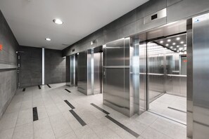 A modern elevator area with metallic doors and a tiled floor.