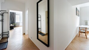 A hallway with a large mirror, a coat rack, a chair, and a table.