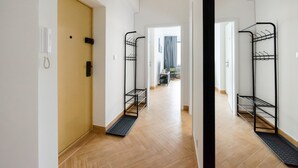 A hallway with wooden flooring, a yellow door, and black metal shelves along the walls.