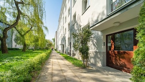A paved pathway lined with trees and a building with large windows and a door.