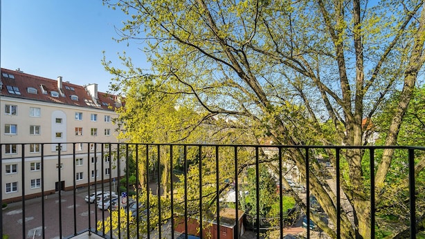 A balcony with a view of parked cars and a building with multiple windows.
