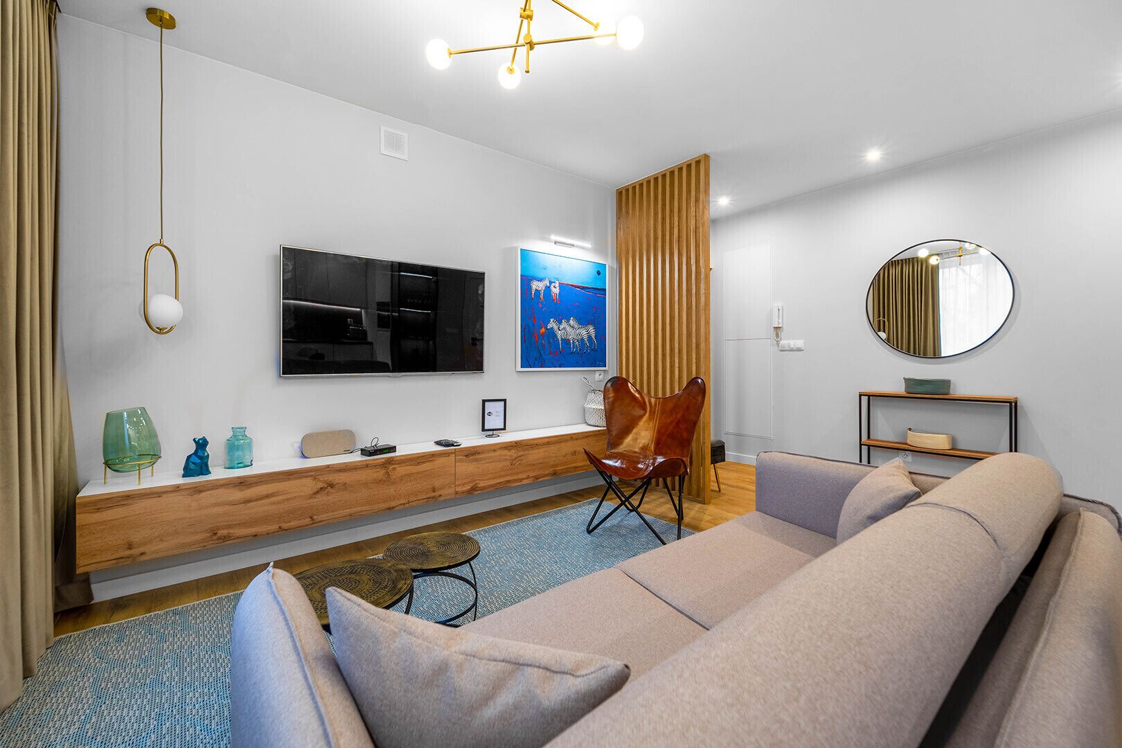 Een moderne woonkamer met een bank, een televisie, een houten console en een spiegel.