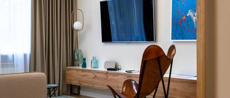 Una habitación de hotel moderna con un escritorio de madera, un televisor montado en la pared y un cuadro con cebras.