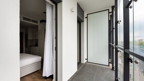 A modern hotel room with a sliding glass door leading to a balcony, a bed, and a white curtain. - New Varsovia Comfort 346 (Warszawa)