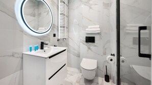 A modern bathroom with a marble floor, a white sink with black handles, a toilet, and a glass shower enclosure. - New Varsovia Comfort 346 (Warszawa)