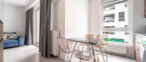 Un apartamento moderno con comedor, sofá y vistas a un edificio a través de amplios ventanales.