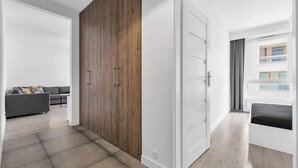 A modern apartment with a grey sofa, a wooden wardrobe, and a white door.