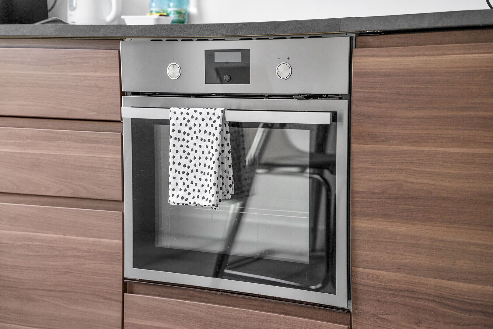 Et moderne køkken med indbygget ovn og stål backsplash.