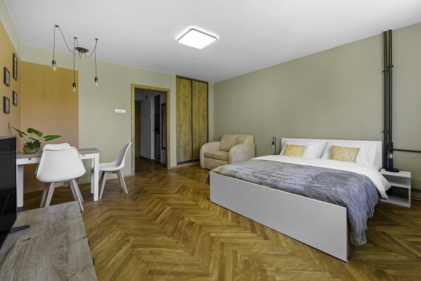 Relax in a serene space with a large bed, a comfortable armchair, and a convenient desk.