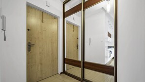 Un pasillo con una puerta de madera y un espejo grande que refleja una cocina.