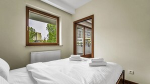 Una habitación de hotel con una cama, un ventanal con vistas a edificios y un radiador.