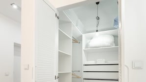 Un dressing sans porte, avec un plancher en bois et des étagères blanches.