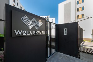 En moderne bygningseingang med et sort gelænder og et skilt, der står "WOLA SKWER".