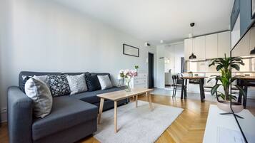 A modern living room with a grey sofa, a wooden coffee table, and a white rug.