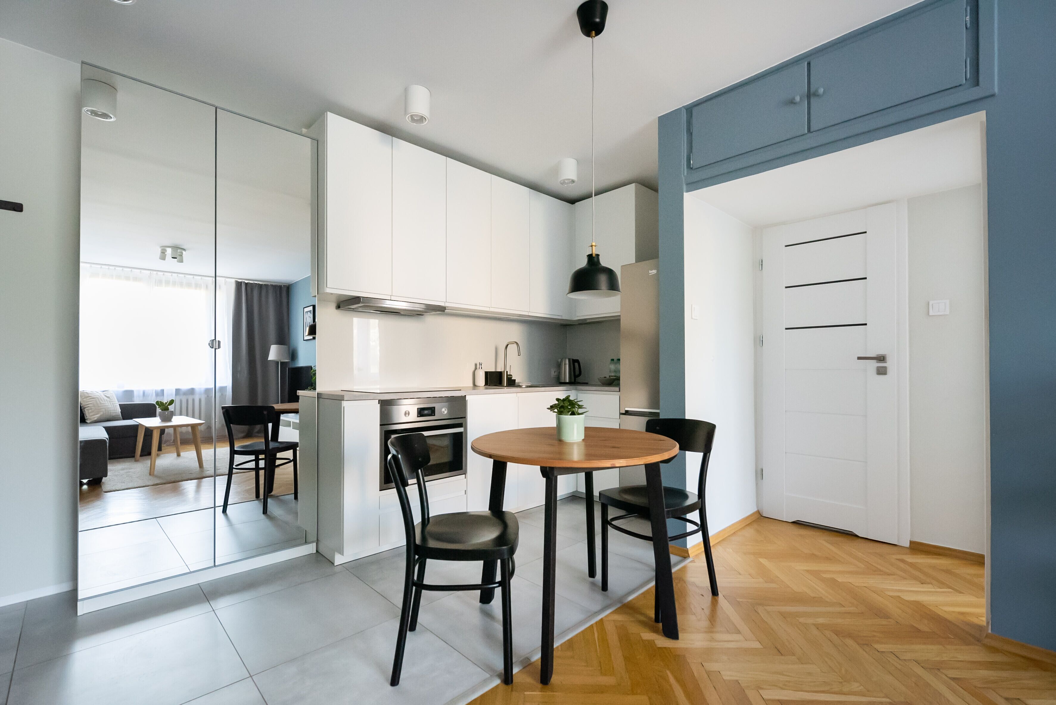 A modern kitchen with white cabinets, a round wooden table, and black chairs.